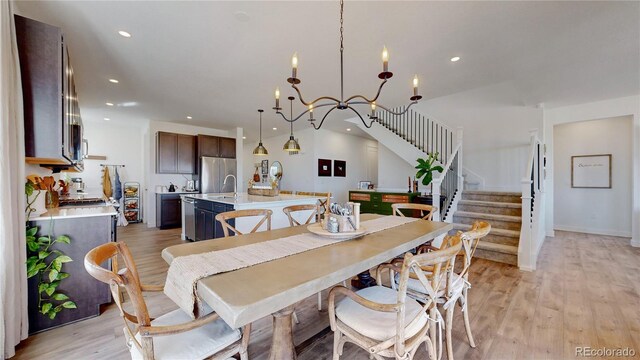 689 Olive St, Broomfield, CO 80023 - dining room with light wood finished floors, recessed lighting, an inviting chandelier, and stairway