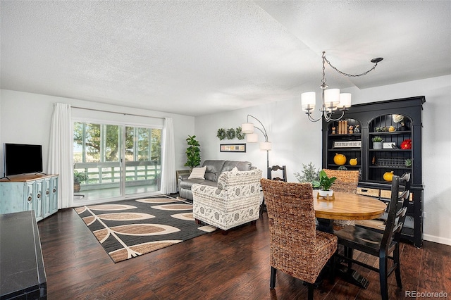 dining area featuring dark wood-style floors, a chandelier, and a textured ceiling