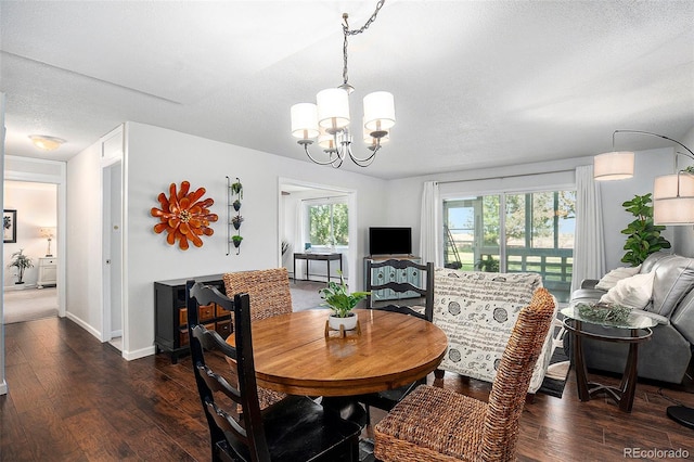 dining area with dark wood-type flooring, a chandelier, a textured ceiling, and baseboards