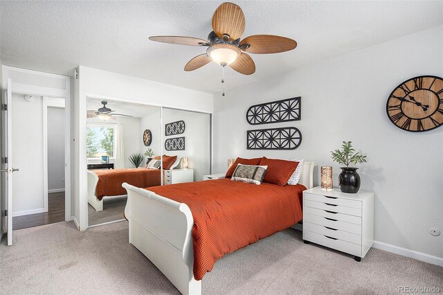 bedroom with a textured ceiling, ceiling fan, a closet, and light colored carpet