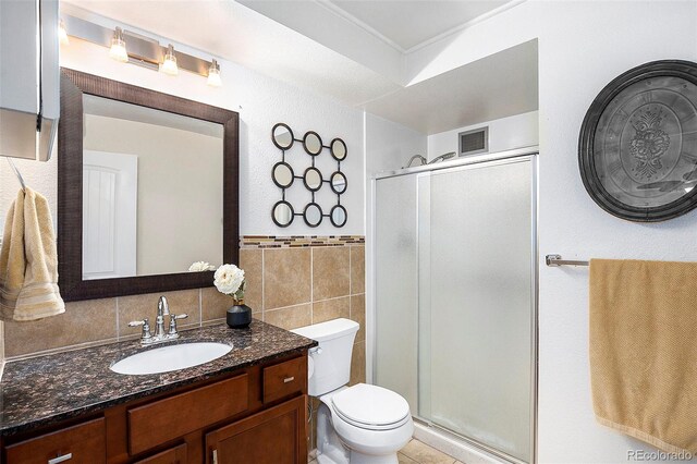 bathroom featuring vanity, toilet, a shower with shower door, and tile walls