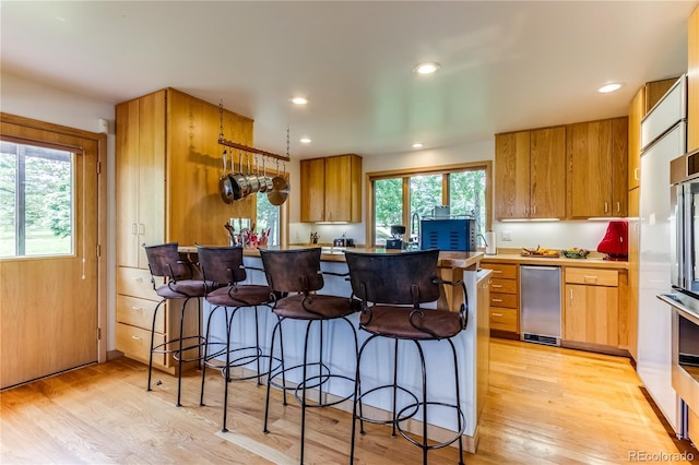 8834 Deiffendeffer Rd, Rye, CO 81069 - kitchen with a breakfast bar, light wood finished floors, a peninsula, recessed lighting, and brown cabinetry