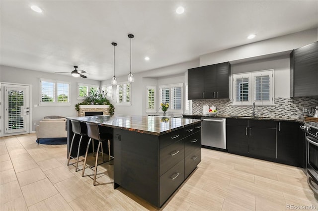 10793 Alcott Way, Denver, CO 80234 - kitchen featuring dark cabinets, appliances with stainless steel finishes, a kitchen breakfast bar, a center island, and ceiling fan