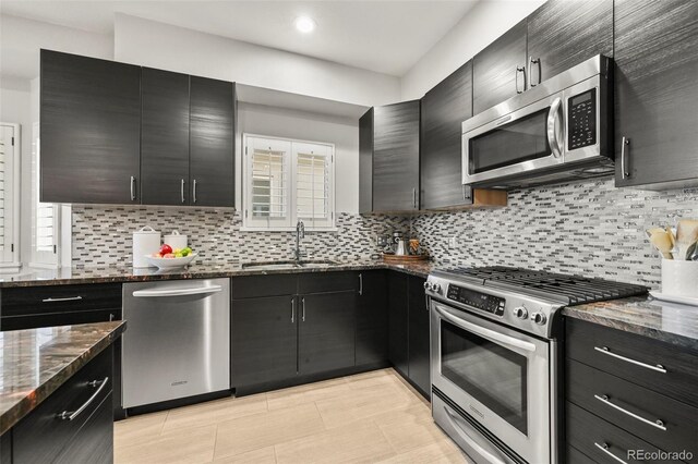 10793 Alcott Way, Denver, CO 80234 - kitchen with stainless steel appliances, dark cabinetry, dark stone counters, decorative backsplash, and healthy amount of natural light