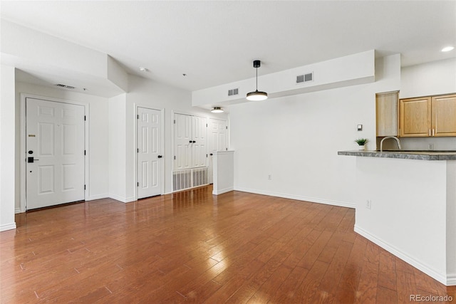 unfurnished living room with visible vents, baseboards, and wood finished floors