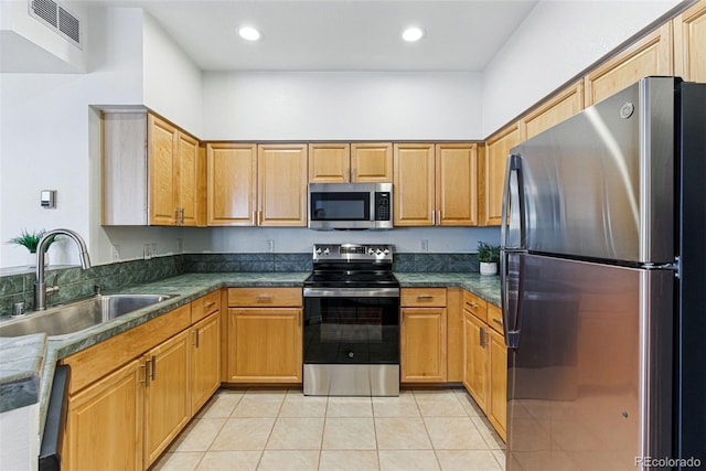 kitchen with dark countertops, visible vents, light tile patterned floors, appliances with stainless steel finishes, and a sink