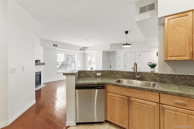 kitchen featuring visible vents, dishwasher, a peninsula, and a sink