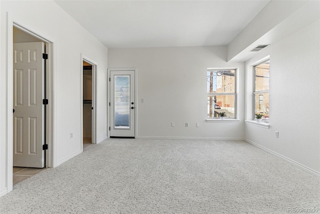 unfurnished bedroom featuring carpet, visible vents, baseboards, a walk in closet, and access to outside