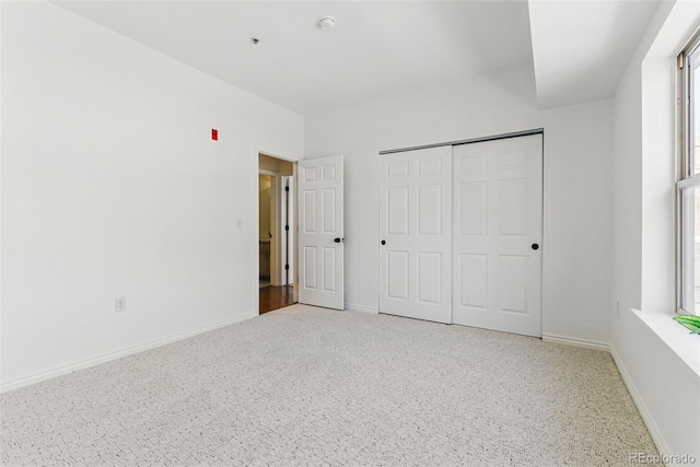 unfurnished bedroom featuring a closet, light colored carpet, and baseboards