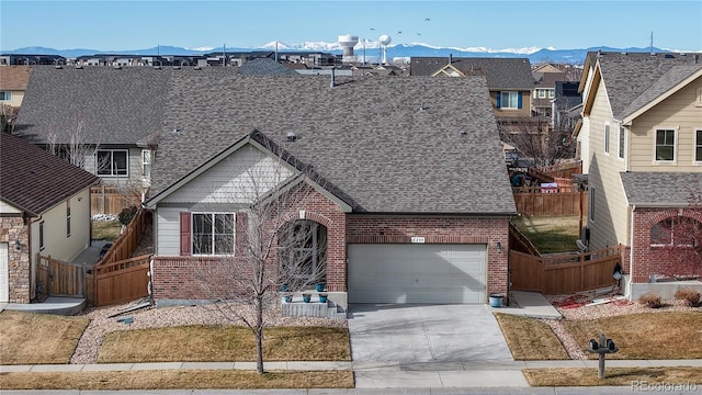 view of front of house featuring a mountain view, brick siding, driveway, and fence