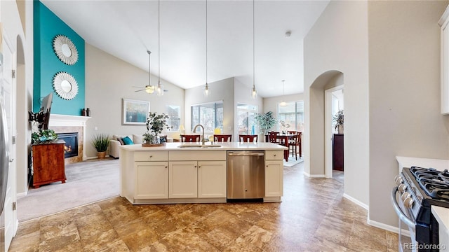 kitchen featuring decorative light fixtures, open floor plan, appliances with stainless steel finishes, a glass covered fireplace, and a sink