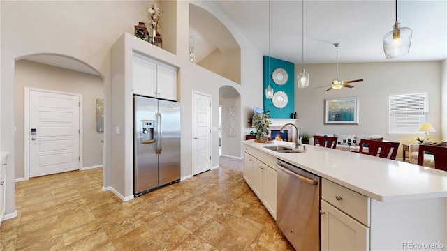 kitchen featuring decorative light fixtures, light countertops, appliances with stainless steel finishes, arched walkways, and a sink