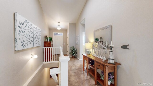 foyer featuring carpet flooring, lofted ceiling, and baseboards