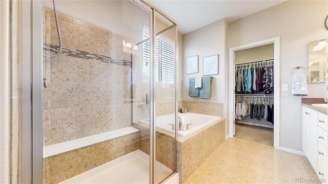 bathroom with a shower stall, vanity, a walk in closet, and a garden tub