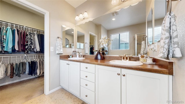 full bath featuring a spacious closet, double vanity, and a sink