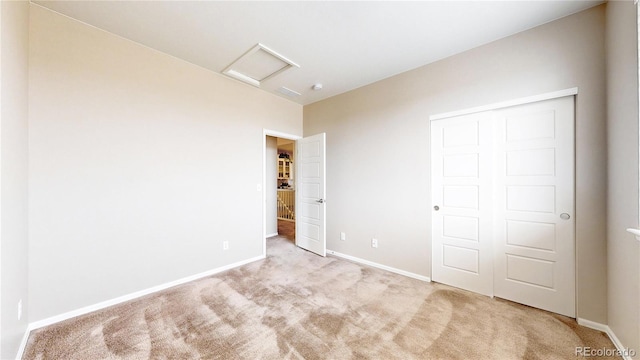 unfurnished bedroom with attic access, baseboards, a closet, and carpet floors