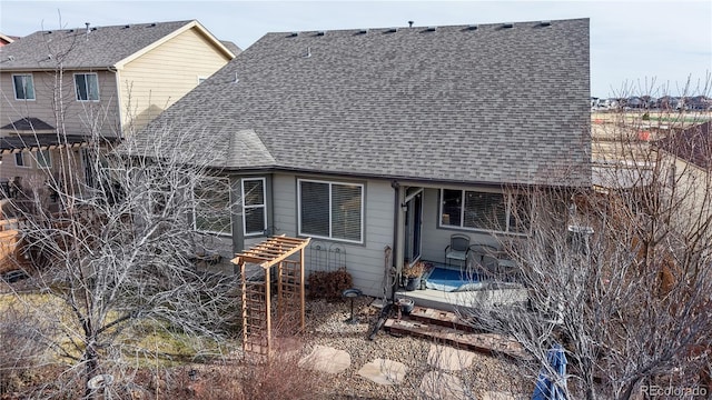 rear view of property with a patio and a shingled roof