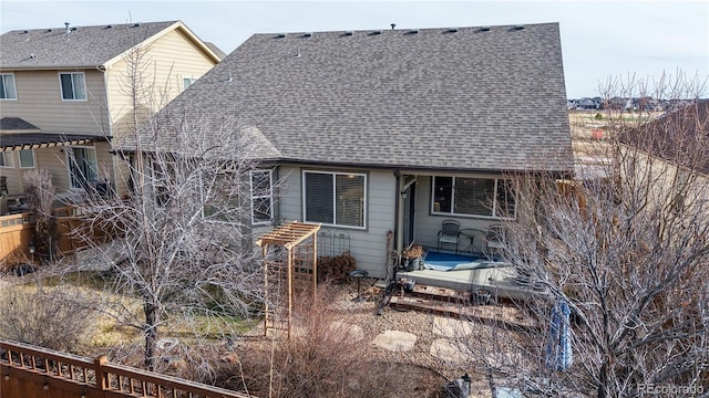 rear view of property with a patio area and roof with shingles