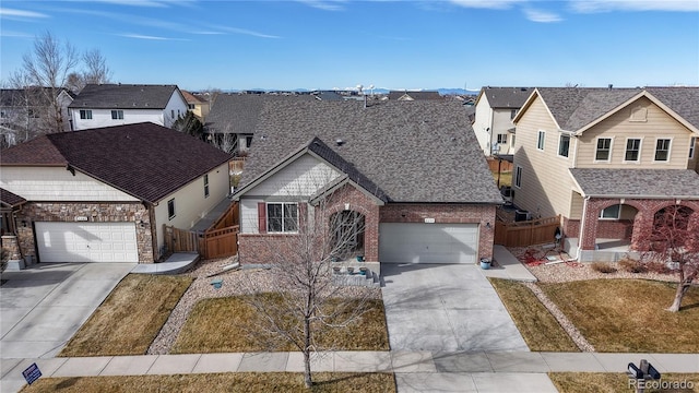 traditional-style house with a residential view, brick siding, concrete driveway, and fence