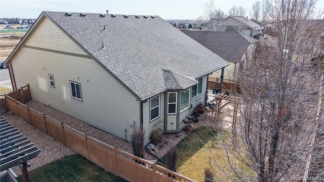 exterior space featuring fence and a shingled roof