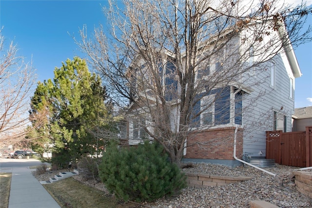 view of home's exterior featuring brick siding and fence