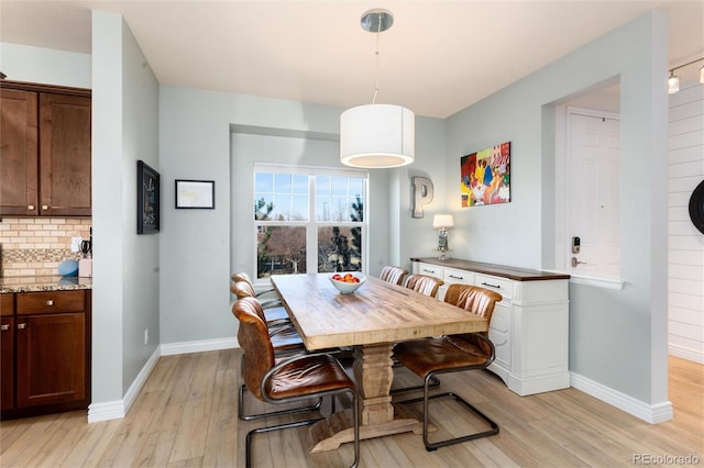 dining room featuring light wood finished floors and baseboards