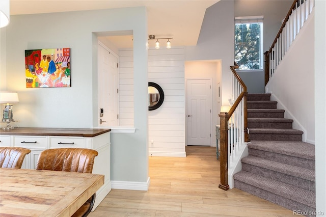 dining area with light wood-type flooring, stairway, and baseboards