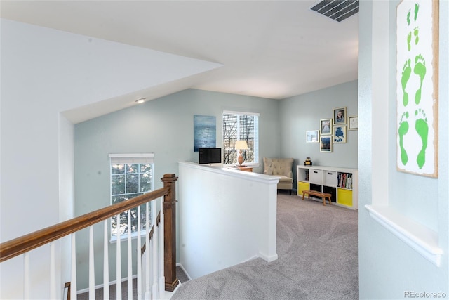 hallway featuring visible vents, carpet, lofted ceiling, and an upstairs landing