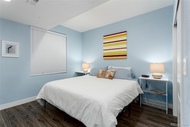 bedroom with visible vents, baseboards, and wood finished floors