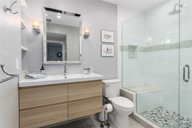 bathroom featuring tasteful backsplash, toilet, a shower stall, vanity, and tile patterned flooring