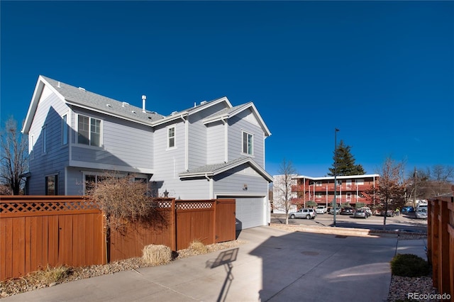 view of home's exterior with a garage, driveway, and fence