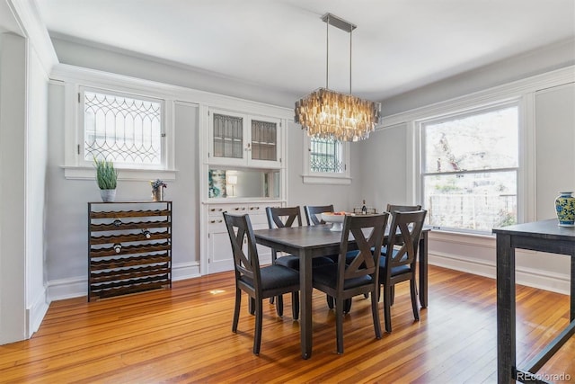 dining area with baseboards, light wood-style flooring, and a notable chandelier