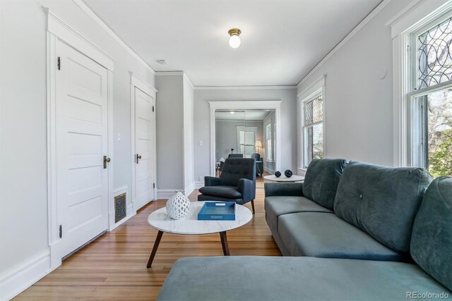 living room featuring light wood-style floors, crown molding, and a healthy amount of sunlight