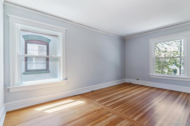spare room featuring baseboards, ornamental molding, and wood finished floors