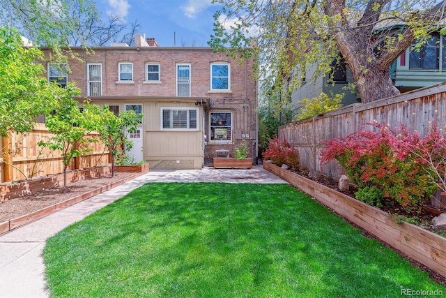 rear view of house with a lawn, a fenced backyard, and a patio