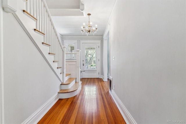 foyer featuring baseboards, ornamental molding, stairs, and hardwood / wood-style floors