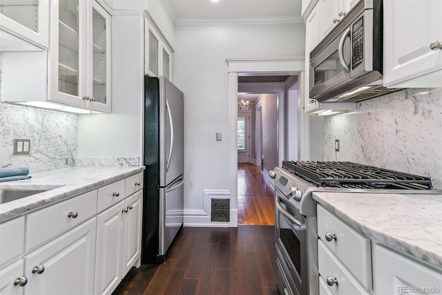 kitchen featuring decorative backsplash, visible vents, crown molding, appliances with stainless steel finishes, and baseboards