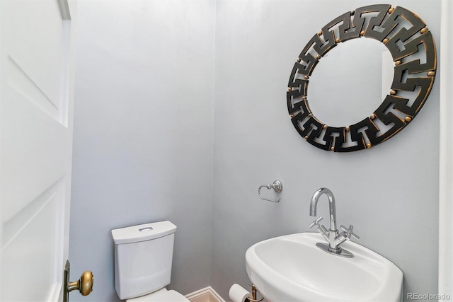 half bath featuring baseboards, a sink, and toilet