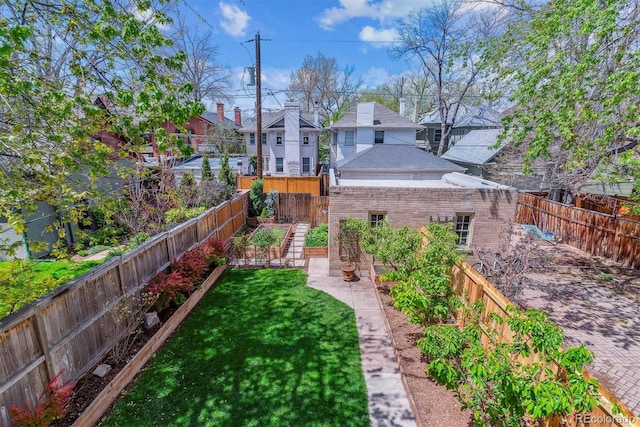view of yard featuring a fenced backyard, a vegetable garden, and a residential view