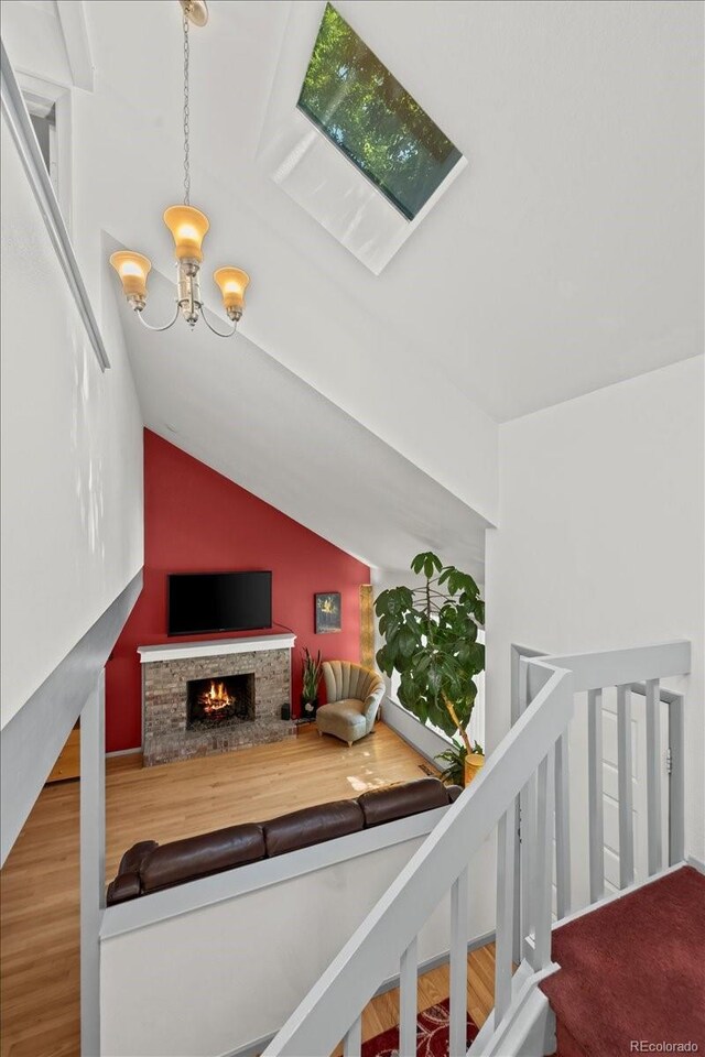 8060 Meadowdale Sq, Niwot, CO 80503 - staircase featuring a chandelier, lofted ceiling, wood finished floors, and a warm lit fireplace