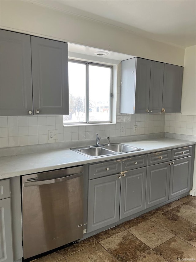 kitchen with tasteful backsplash, dark tile flooring, dishwasher, sink, and gray cabinets