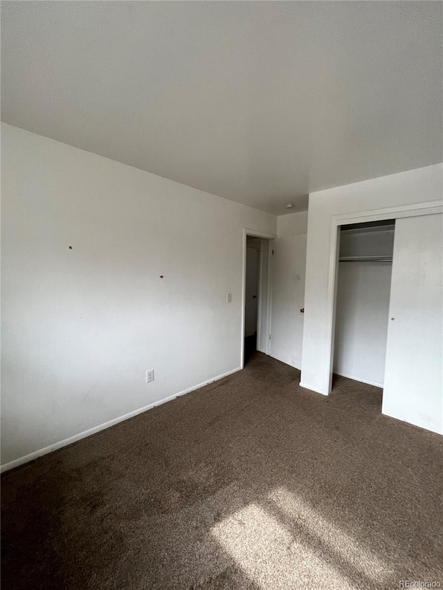 unfurnished bedroom featuring a closet and dark colored carpet