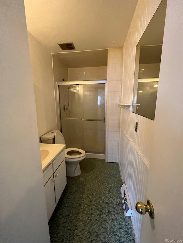 bathroom with tile flooring, toilet, vanity, and walk in shower