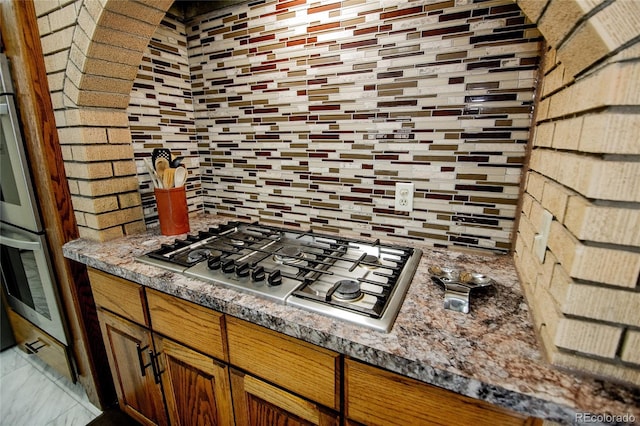 kitchen with stainless steel appliances, tasteful backsplash, and dark stone counters