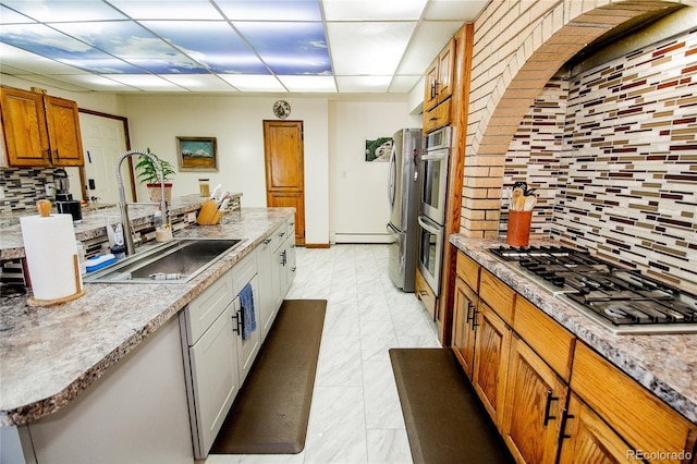 kitchen with a paneled ceiling, backsplash, appliances with stainless steel finishes, and sink