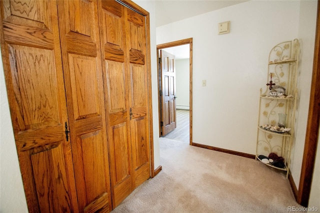 hall with light carpet and a baseboard heating unit