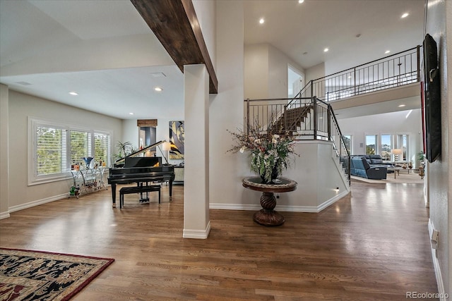 stairs with recessed lighting, baseboards, wood finished floors, and a towering ceiling