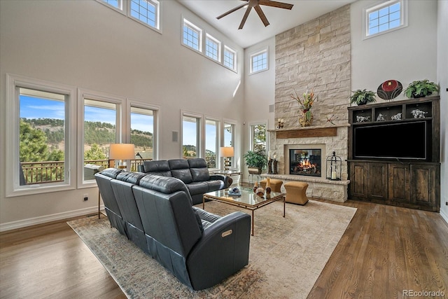 living area with baseboards, a ceiling fan, wood finished floors, and a fireplace