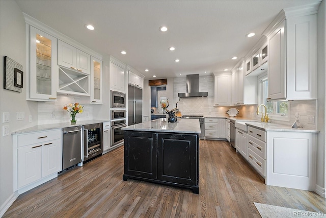 kitchen with wine cooler, built in appliances, white cabinets, and wall chimney exhaust hood