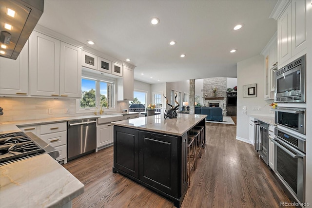 kitchen with dark cabinetry, a sink, appliances with stainless steel finishes, white cabinetry, and tasteful backsplash